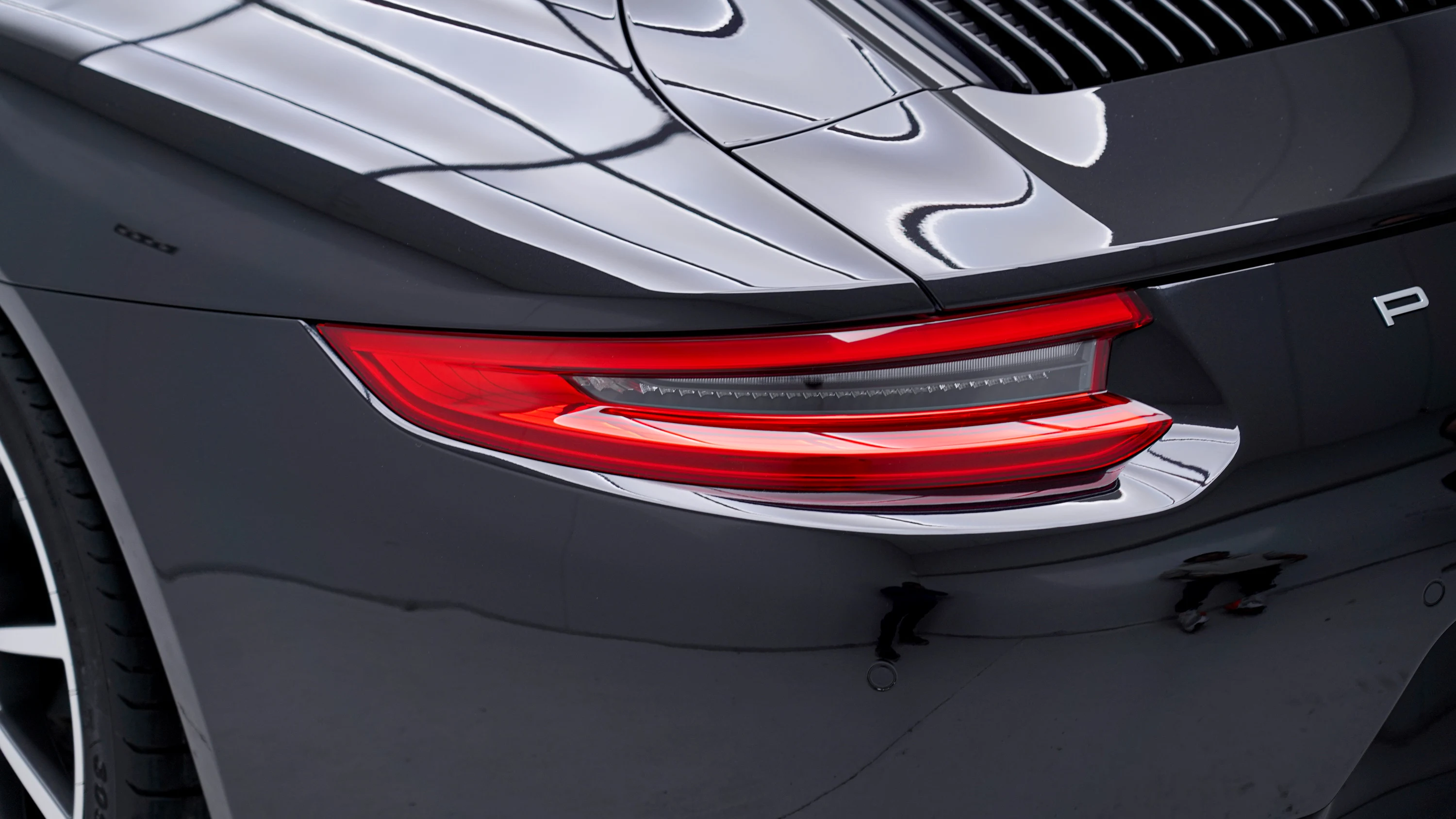 Rear light and rear quarter of a dark Porsche