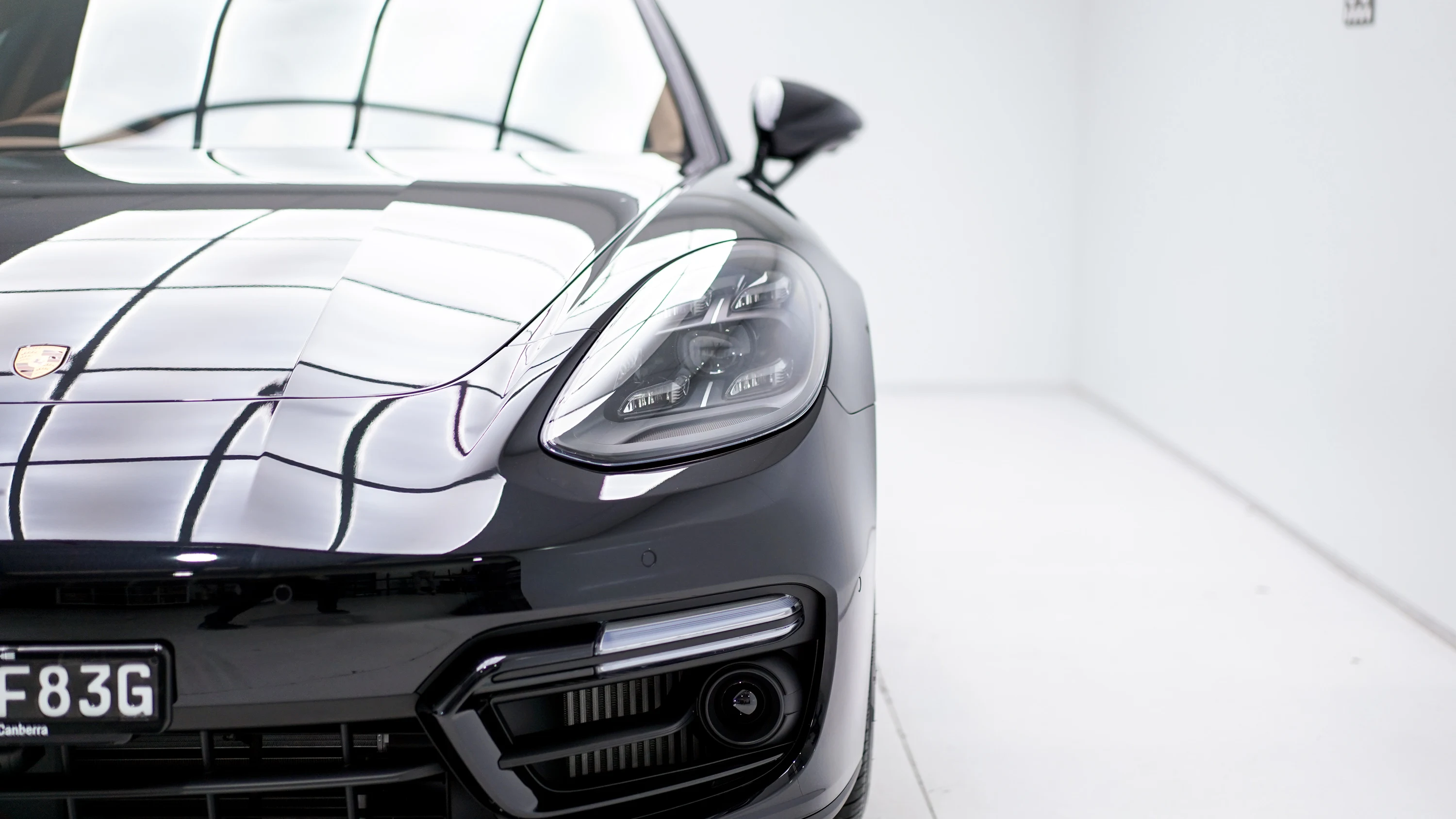 Front headlight and bonnet of a dark Porsche in the workshop