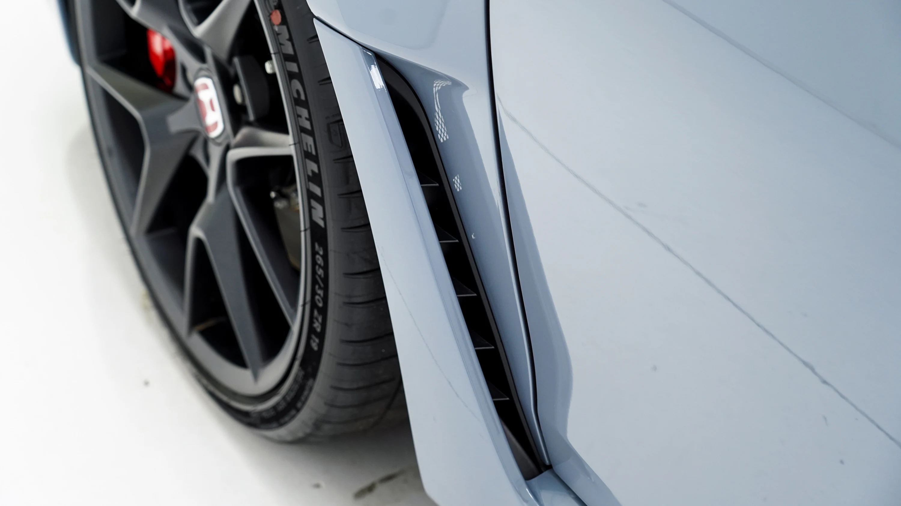 Front wheel and side vent on a light blue car